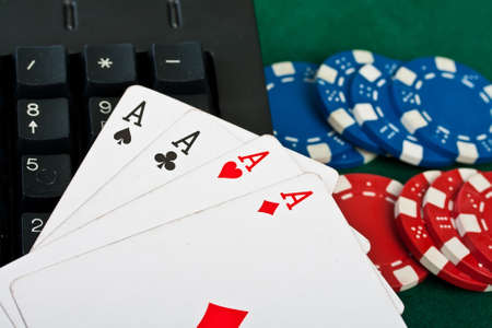 Fragment of the black modern keyboard of computer with gamble chips and cards.の写真素材