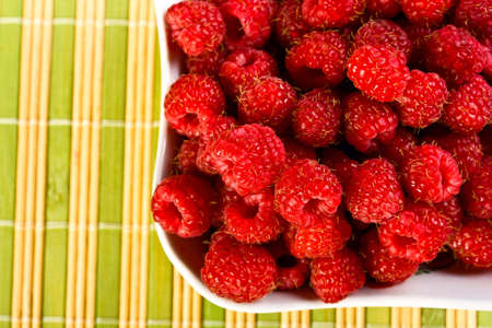 ripe wild raspberries on a white napkin on the grassy saucerの写真素材