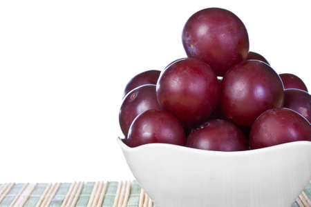 ripe juicy plums on a white napkin on the grassy saucerの写真素材