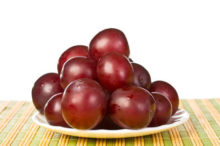 ripe juicy plums on a white napkin on the grassy saucerの写真素材