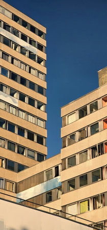 Two tall buildings with windows in sandy light color. Buildings are opposite clear cloudless sky. Buildings with open windows. Vertical modernistic photo.の写真素材
