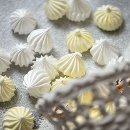 Airy meringue in form of drop, close up shot. White and yellow meringues on parchment paper, fresh from oven. Delicate dessert, egg sweets. Sweet pastries, Food background. Soft focus.の写真素材