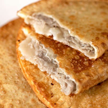 Puff pastry pie stuffed with meat filling. Fresh cheburek, fried bread with meat. Delicious snack or nutritious lunch on the run. Takeaway food concept. Square format. Soft focus.の写真素材