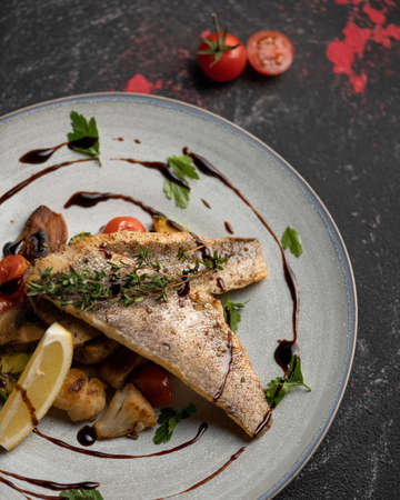 Dietary fish dish, hearty and healthy lunch. Fried river fish with vegetables. Plate of cooked Fish...
