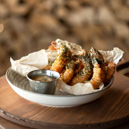 Fried king prawn or shrimp platter with sauce on blurred background. Seafood concept. Spicy oriental dish, Pan-Asian cuisine.の写真素材
