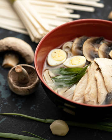 Exotic soup with meat, Champignon mushrooms and eggs. Bowl of hot and Spicy oriental dish. Pan-Asian cuisine. Soft focus. Vertical format.の写真素材