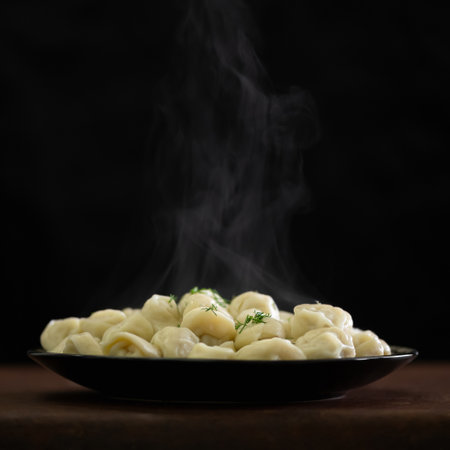 Pile of Hot cooked dumplings or ravioli sprinkled with dill. Plate with Convenience Food isolated on black background. Copy space on top of image. Soft focus. Dough stuffed.の写真素材