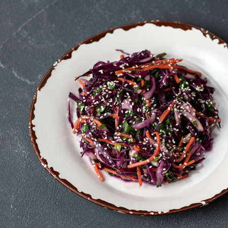 Mixed fresh vegetables and greens on clay plate. Top view. Vitamin salad of red cabbage, carrots or...