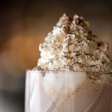 Airy foam on milkshake cocktail sprinkled with grated chocolate. Close up of Puffy whipped cream...