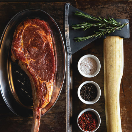 Flat lay, Tomahawk or t-bone steak, cooking process. Butcher ax for cutting meat, large piece of raw...