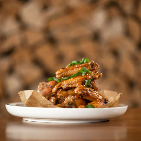 Appetizing roasted or fried chicken wings sesame seeds and onion. Soft focus. Food concept. Square...