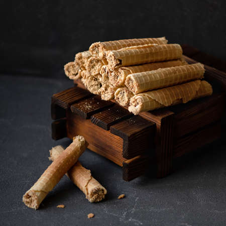 Pyramid of waffle rolls on gray background. Sweet rolls filled or stuffed with condensed milk. Wafer rolls or tubes. Soft focus.の写真素材
