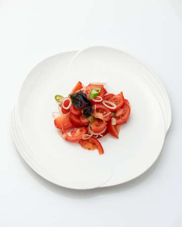 Platter with Fresh tomato, onion and basil salad isolated on white background. Healthy vegetarian food. Dietary vegetable meals. Vitamin vital food. Top view. Copy space. Vertical format.の写真素材