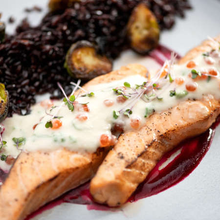Fried salmon fillet with microgreens, sauce and red caviar. Seafood concept. Close-up shot. Square format. Soft focus.の写真素材