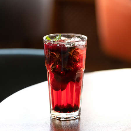 Backlit red iced drink. Glass on table, blurred background. Healthy fresh berries juice or soft drink. Bright colors of nature. Soft focus. Copy space.の写真素材