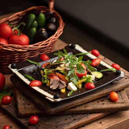 Salad of ham, herbs and fresh vegetables. Food plate on wooden board and table. Copy space. Soft focus.の写真素材