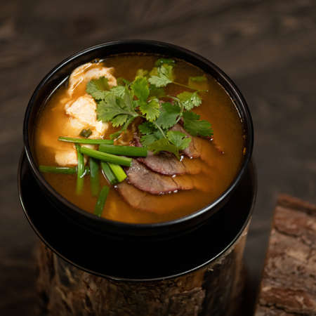 Meat thai soup with onion and parsley. Close up shot bowl with Spicy dish. Oriental lunch. Pan-Asian...
