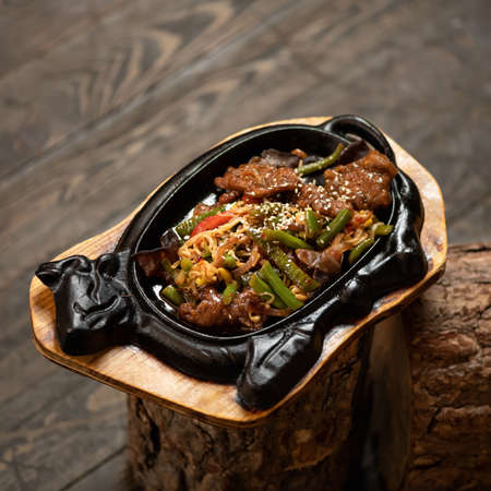 Pan-asian cuisine, spicy food. Vegetables fried in wok pan with noodles and sesame seeds. Food in cow shape plate. Soft focus. Copy space.の写真素材