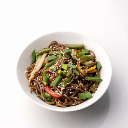 Brown spaghetti or pasta with vegetables and sesame seeds. Bowl isolated on white background. Pan-asian cuisine, spicy food.Top view.の写真素材