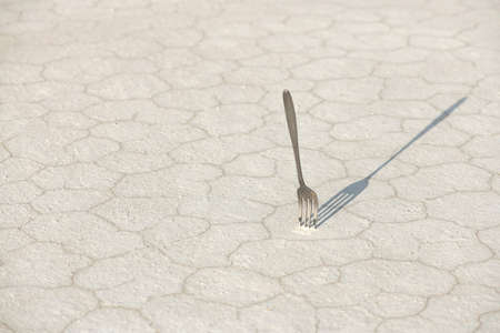 Fork stuck in cracked desert sandy ground. Problem of depletion of soil resources. Arid climate. Global warming concept. Horizontal format.の写真素材