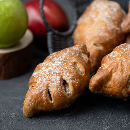 Baked stuffed buns, pastries sprinkled with Sugar powder on gray table. Sweet food. Square format. Soft focus.の写真素材