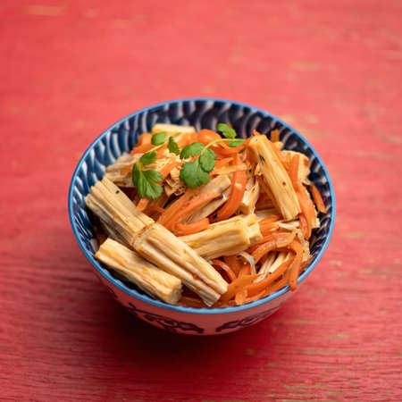 Thai salad with carrots and celery. Bowl of eastern food on red background. Soft focus.の写真素材