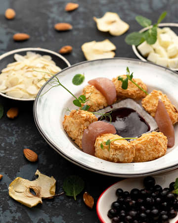 Platter with appetizer, delicious pieces in almond petals and herbs on table. Soft focus. Close-up shot. Vertical format.の写真素材