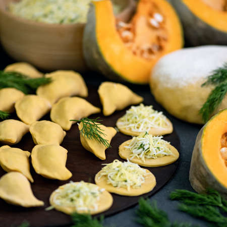 Convenience Food, cooking process. Raw Pumpkin Dumplings with eggs and dill filling on kitchen table. Soft focus. Close-up shot.の写真素材