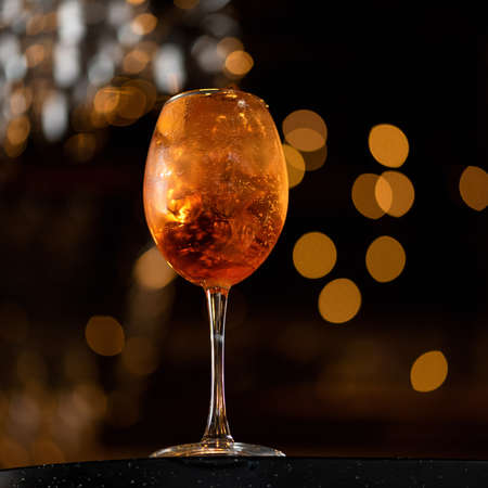 Backlit Golden alcohol drink on black blurred background. Glass of bubbling beverage. Side view. Copy space. Soft focus.の写真素材