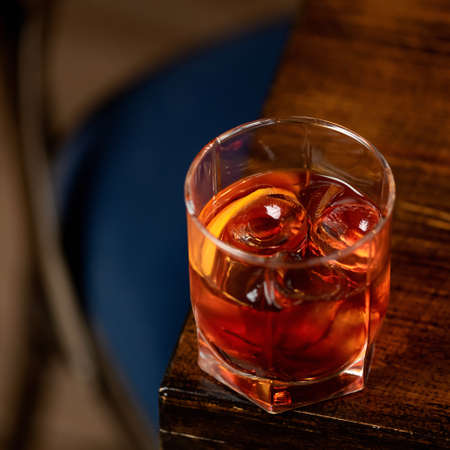 Golden whiskey with ice and lemon in glass on wooden table. Expensive alcoholic shot. Copy space. Soft focus.の写真素材