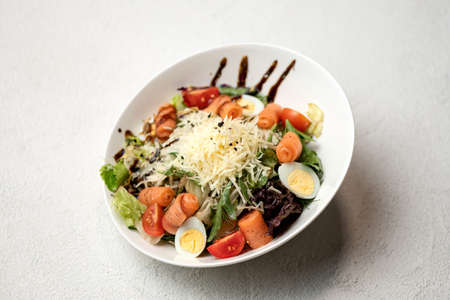 Caesar salad with red fish and grated Parmesan cheese. Food plate on white background. Horizontal format.の写真素材