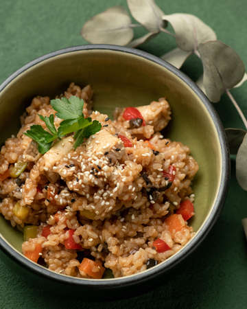 Stewed rice with meat or chicken fillet, vegetables and herbs. Asian food. Pan-Asian cuisine. Close-up shot. Soft focus. Vertical format.の写真素材