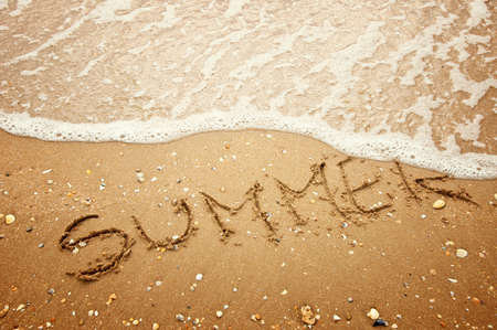 Summer written in the sand of beach and waveの写真素材
