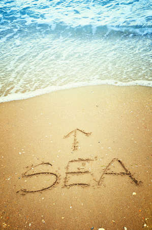 Sea and arrow written in the sand on the beachの写真素材