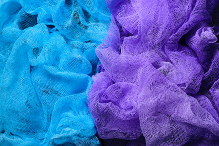 Handmade dyed textured gauze fabric background. Blue and purple colors. Top view. Close up.の写真素材