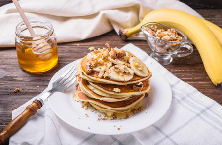 Pancakes with banana, walnuts and honey. Healthy breakfast. On dark wooden table background.の写真素材