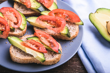 Healthy toast with avocado and tomatoes slices. Four toasts on plate, organic healthy food concept.の写真素材