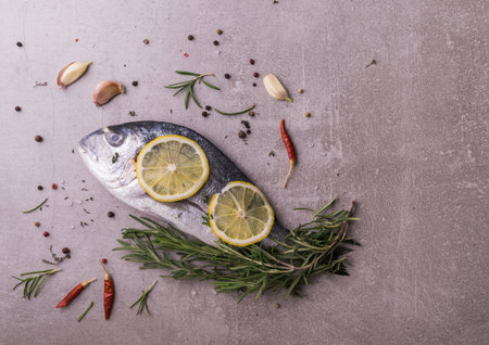 Fresh dorado fish. Dorado and cooking ingredients - rosemary, spices, lemon, garlic, thyme, herbs....
