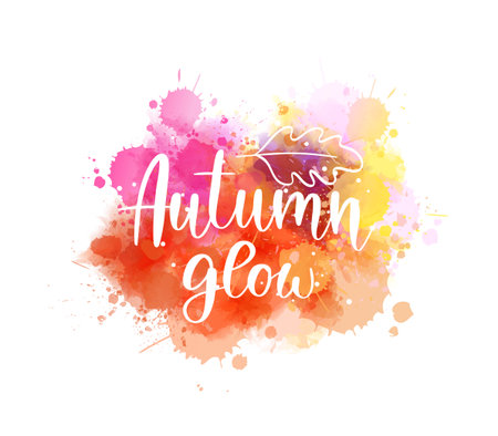 Colorful handwritten text 'Autumn glow' on watercolor orange paint splashes. Seasonal modern calligraphy lettering textのイラスト素材