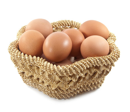 Easter eggs in brown basket on a white backgroundの写真素材