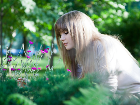 Portrait of a girl who smells flowers. A flower bed in the park.の写真素材