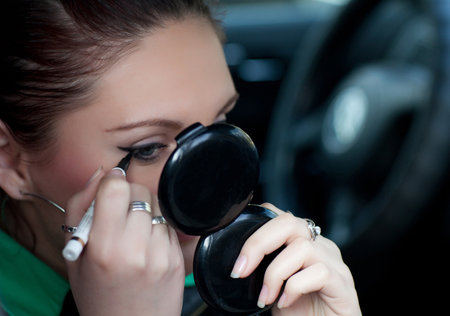 The girl is doing makeup in the carの写真素材