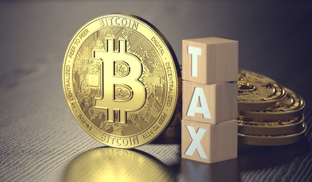 Bitcoin standing next to wooden blocks with TAX letters. Taxes on bitcoin investments concept. 3D renderingの写真素材