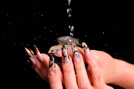 beautiful female nails and falling drops of waterの写真素材