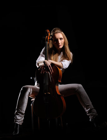 attractive girl with cello isolated over black backgroundの写真素材