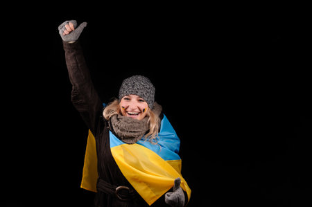 Portrait of attractive girl with ukrainian flag, over black background. Patriotism, independence, revolution in Ukraine. の写真素材