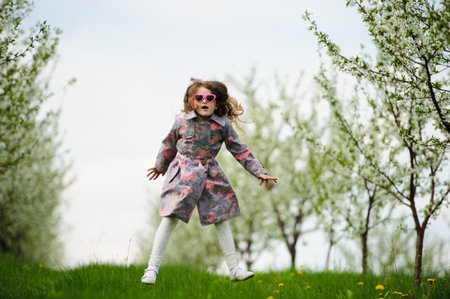 Portrait of Little pretty girl in the green blooming gardenの写真素材