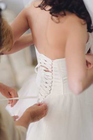 Bridesmaid is helping the bride to dressの写真素材