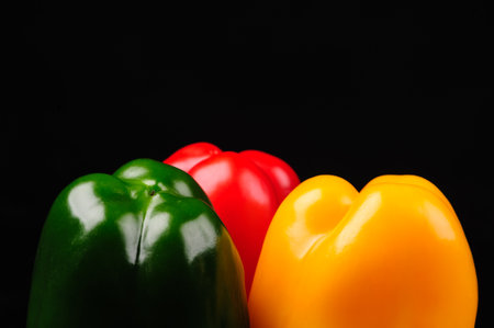 yellow, red and green  peppers on a black backgroundの写真素材