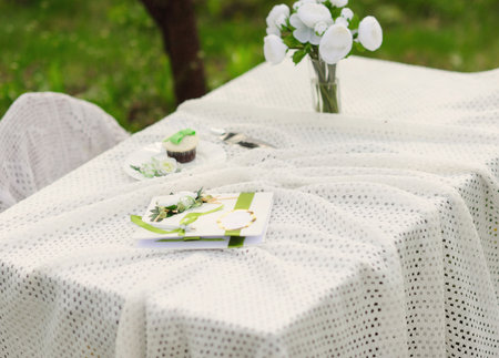 bouquet of roses and  cake on plate  on the table in the blooming garden